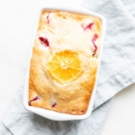 Small ceramic loaf pan of cranberry orange bread, resting on a pale blue linen towel.