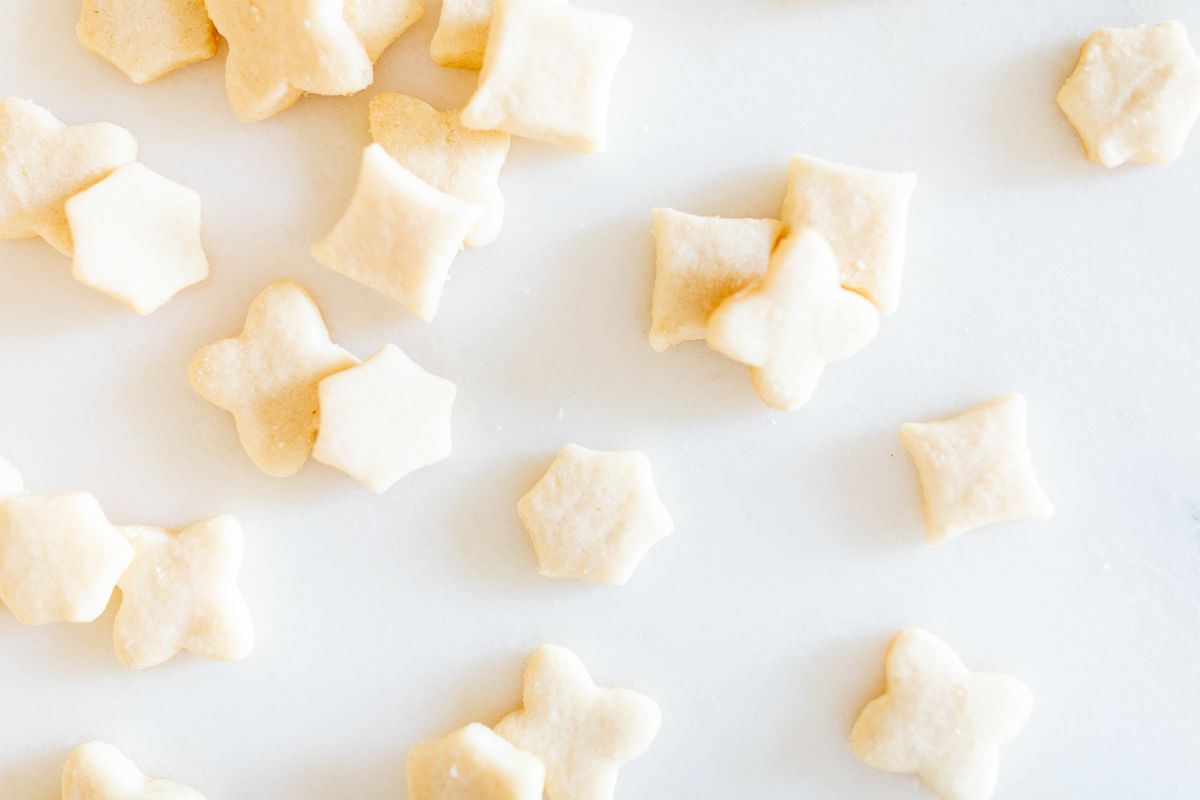 Tiny cutout shortbread elf on the shelf cookies on a marble countertop.