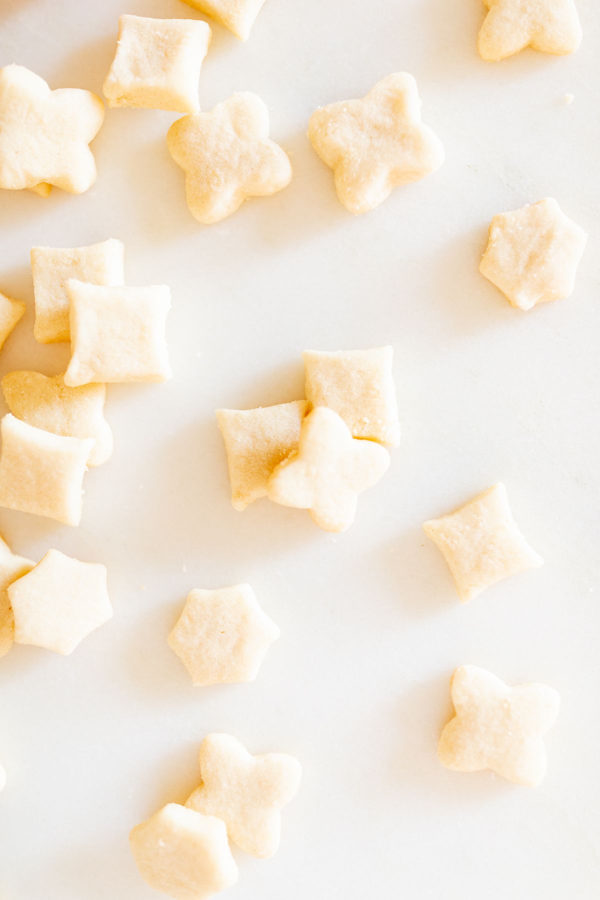 Tiny cutout shortbread elf on the shelf cookies on a marble countertop.