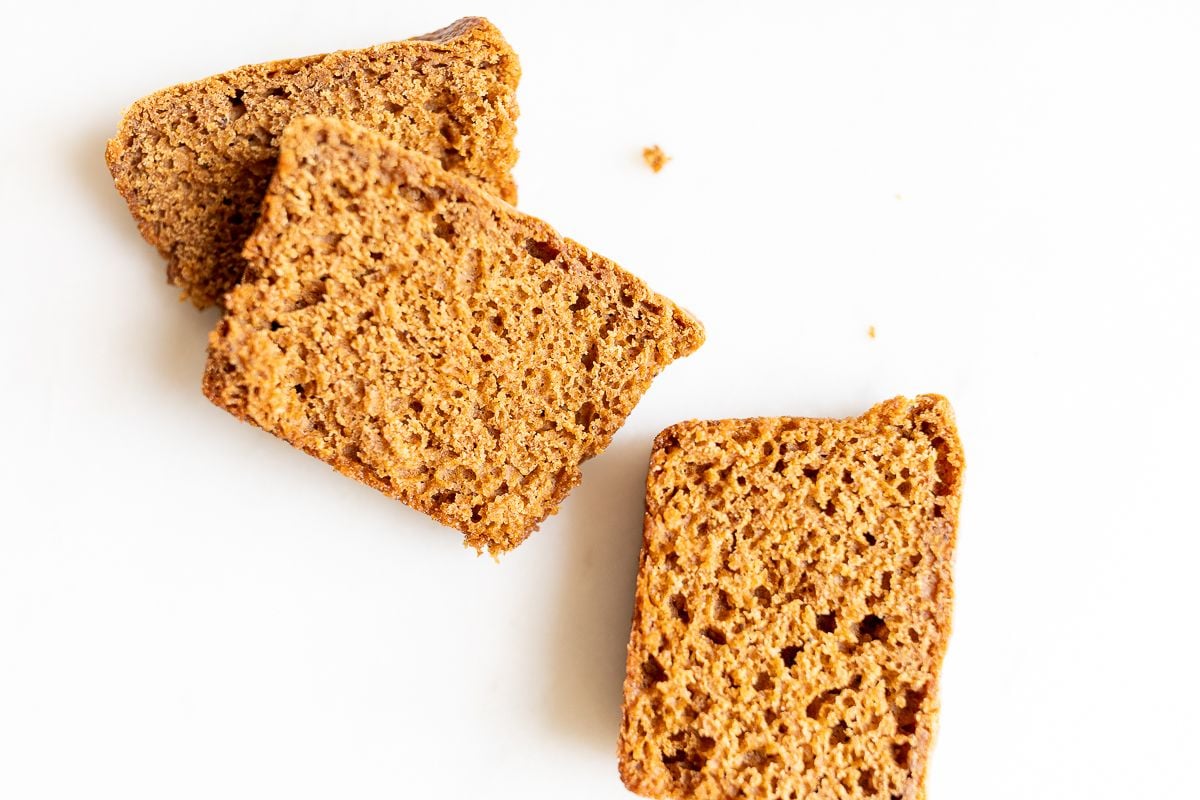 Slices of a gingerbread loaf recipe on a white marble countertop.