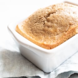 A quick latte bread in a small white loaf pan, on a blue kitchen towel.