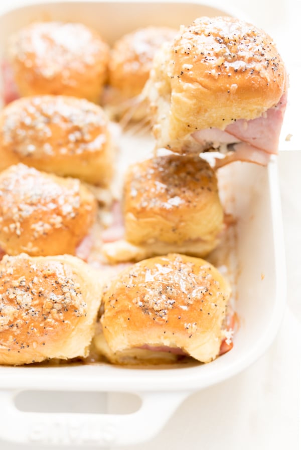 Hot ham and cheese sliders in a white baking dish.