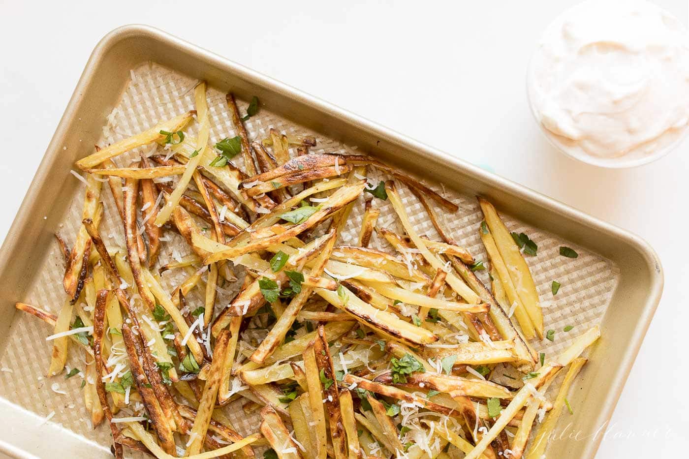 Truffle fries on a sheet. pan, topped with parmesan cheese and parsley.