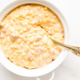 A white casserole dish full of cheesy corn casserole