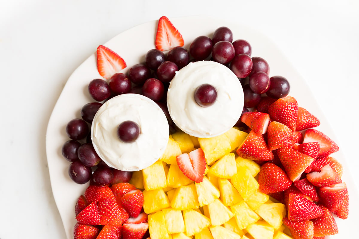 A fruit tray shaped into an owl, featuring cream cheese fruit dip as the owl's eyes.