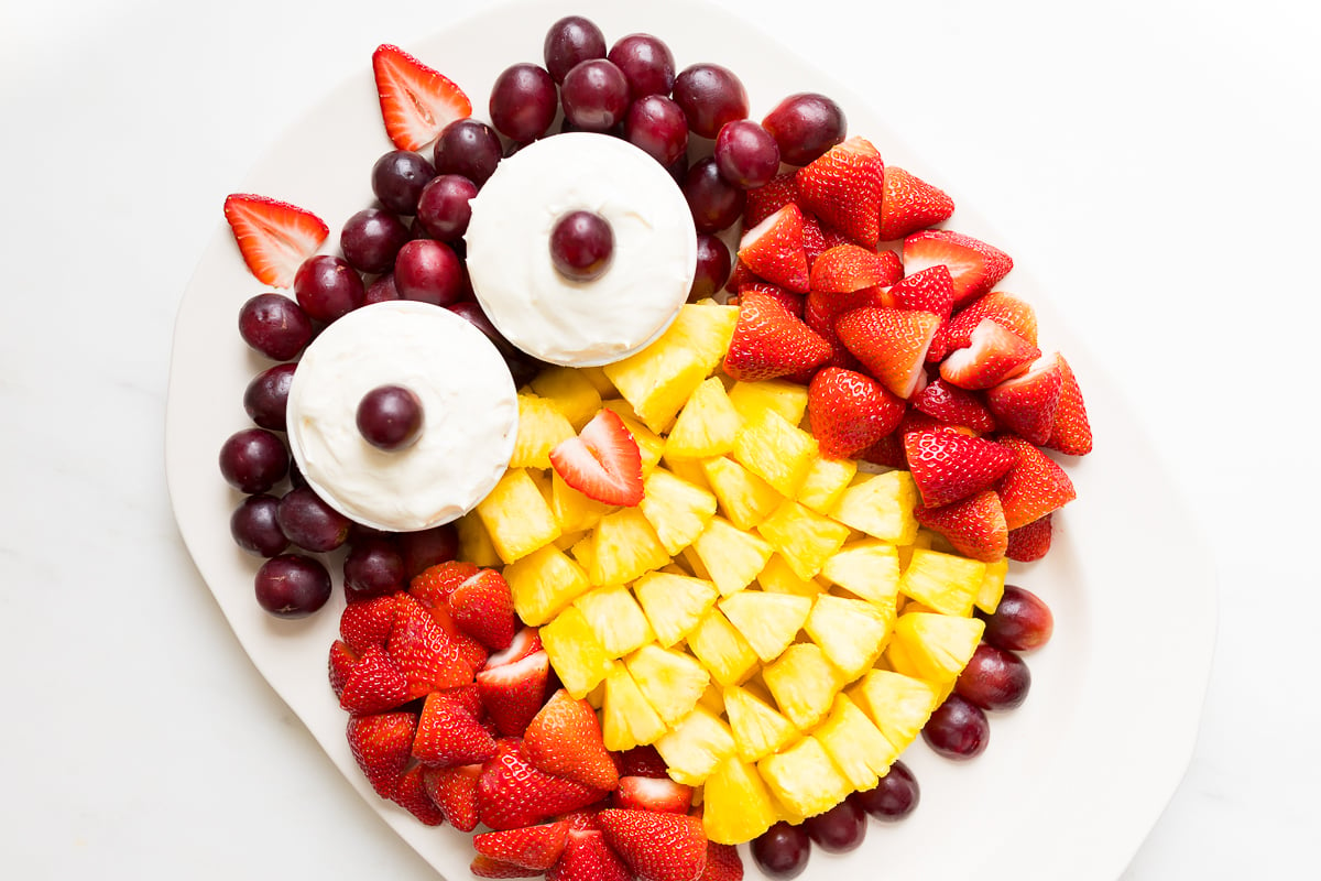 A fruit tray shaped into an owl, featuring cream cheese fruit dip as the owl's eyes.