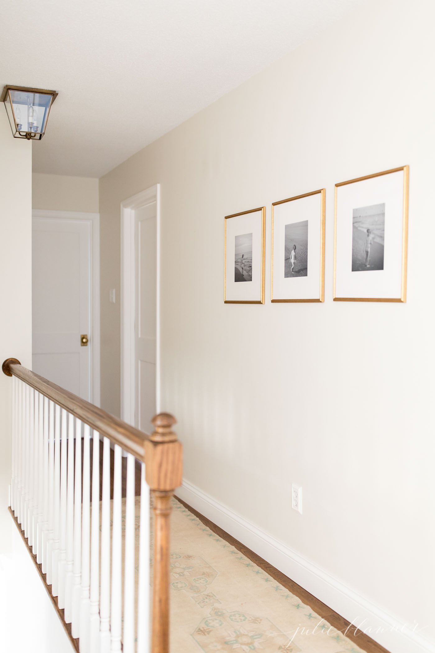 A white hallway with brass framed photos on the wall