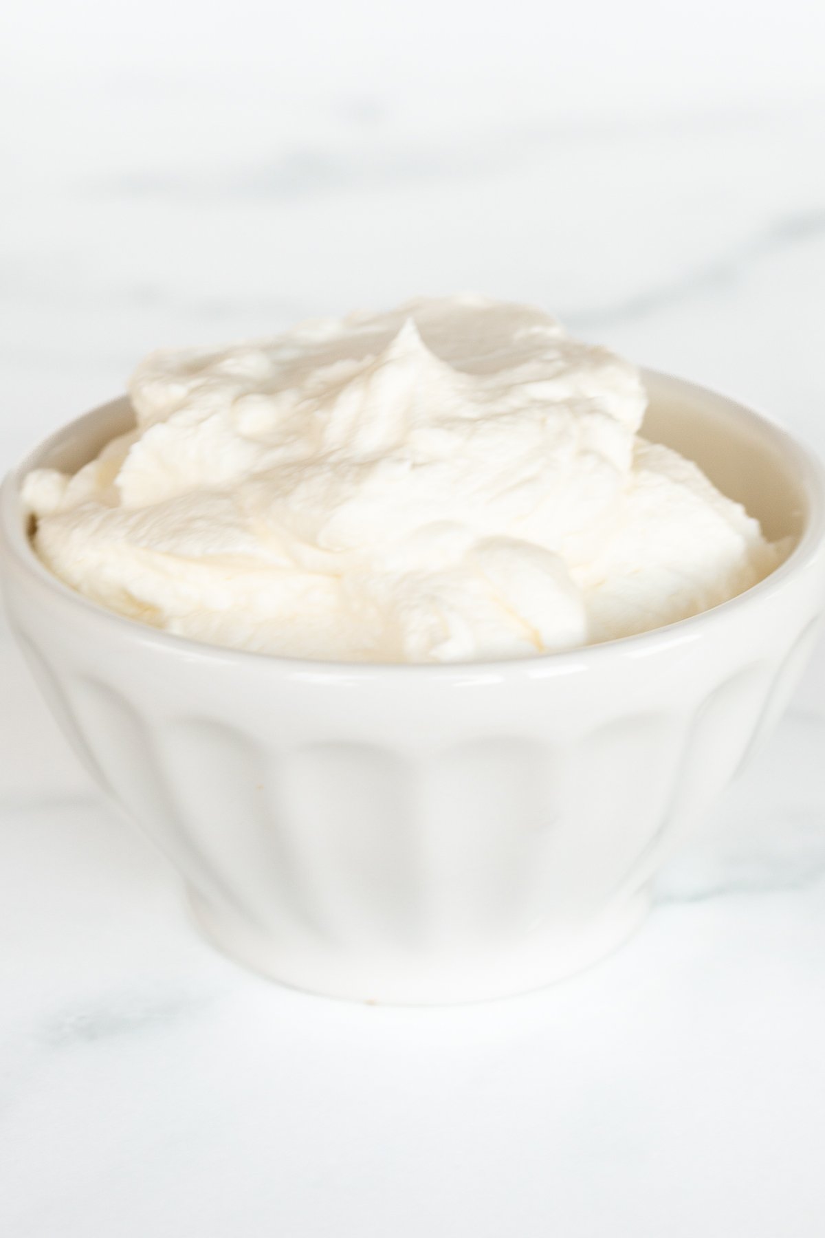 A white bowl full of homemade whipped cream.