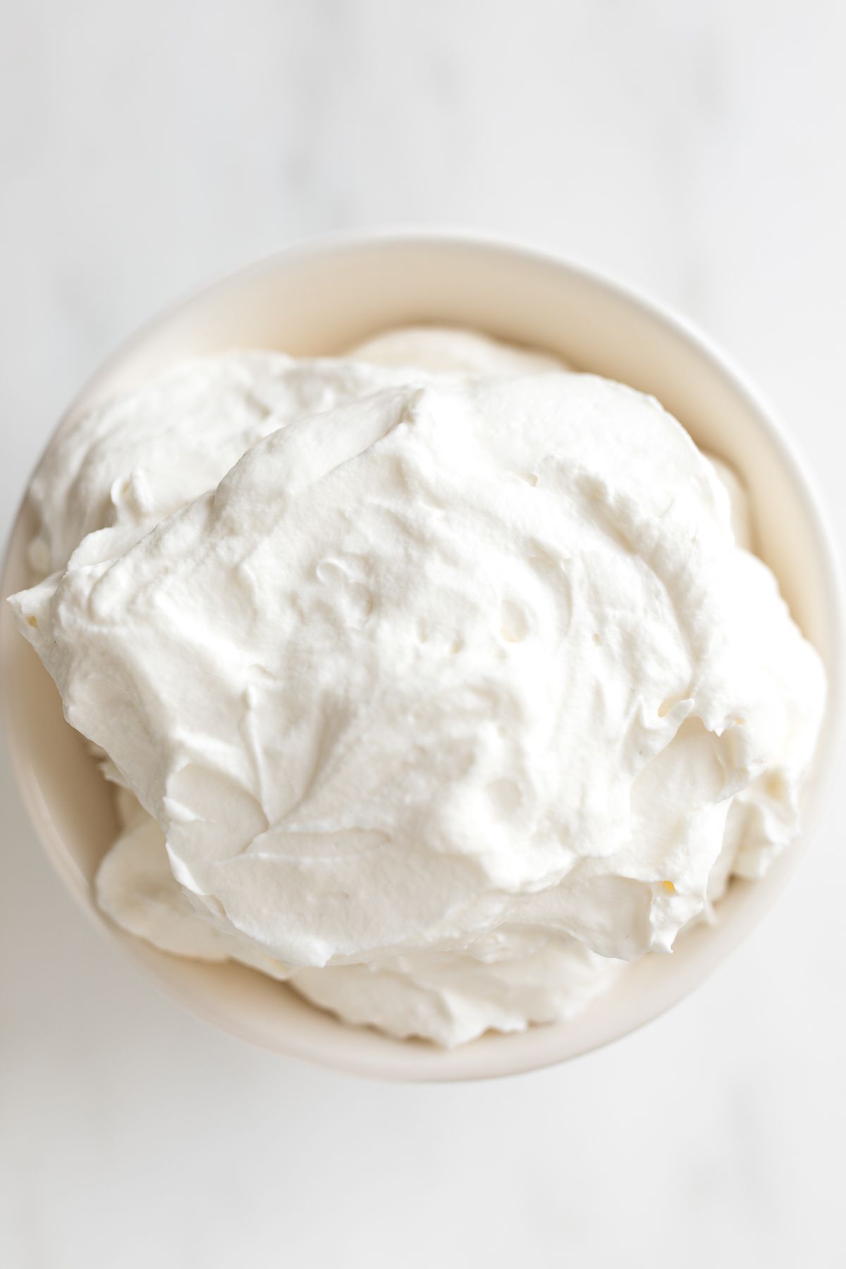 A white bowl full of homemade whipped cream.