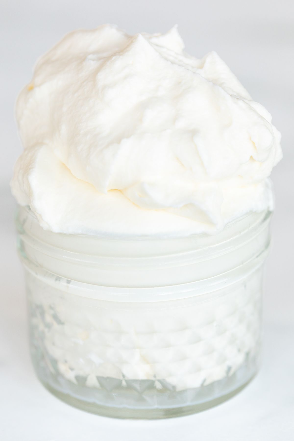 A small glass jar full of homemade whipped cream.