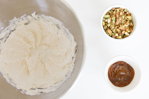 A bowl of icing and a bowl of pistachios.