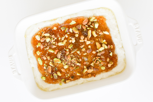 A white dish with pistachio goat cheese spread.