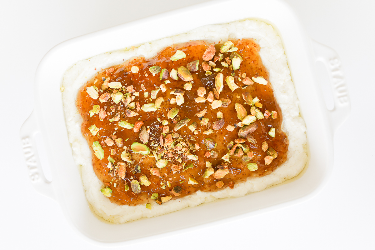 A white dish with pistachio goat cheese spread.
