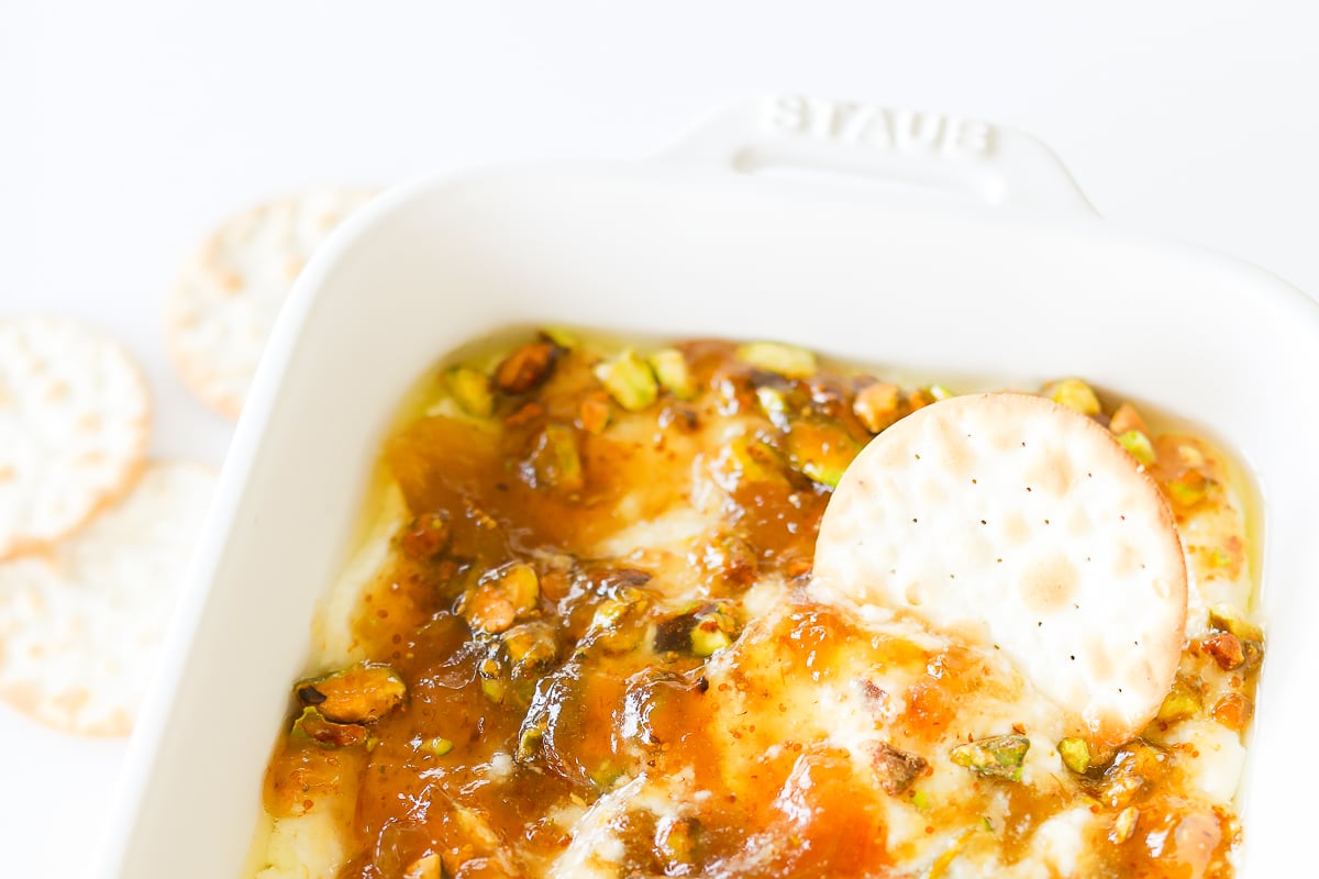 A white dish with a cracker and dip.