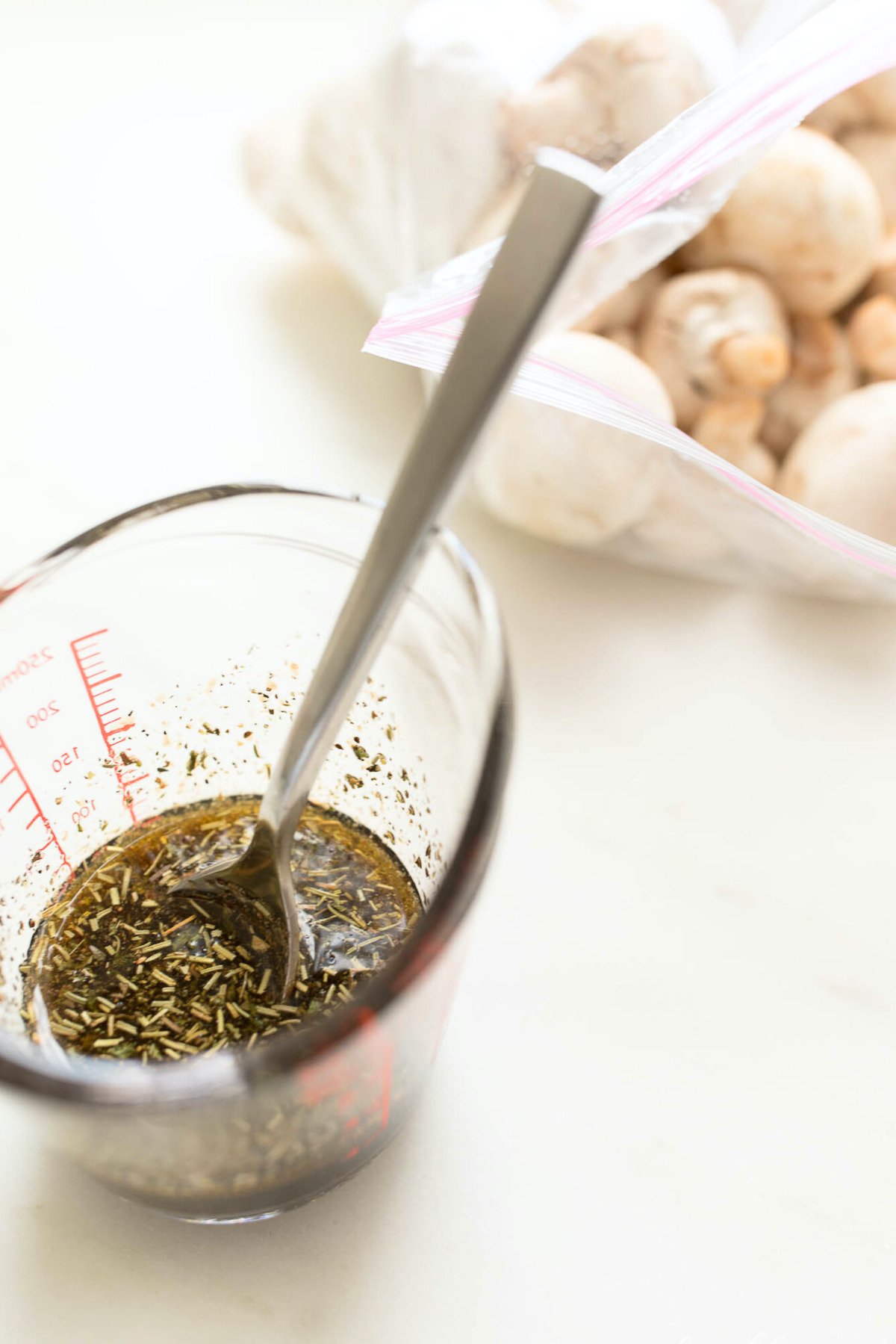 A measuring cup with a bag of mushrooms next to it, ready for roasting in the oven.