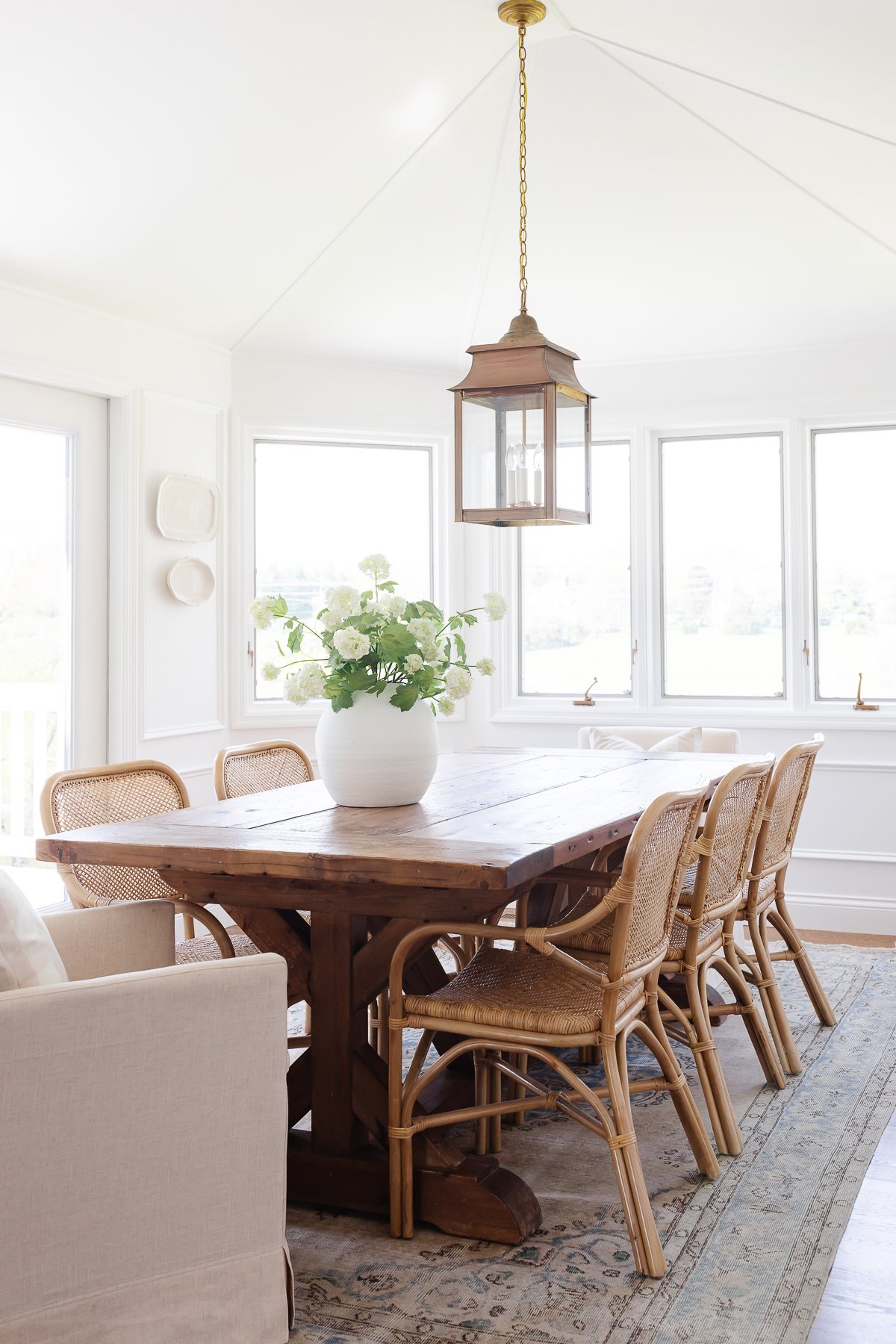 A white windowed breakfast nook with a wood dining table.