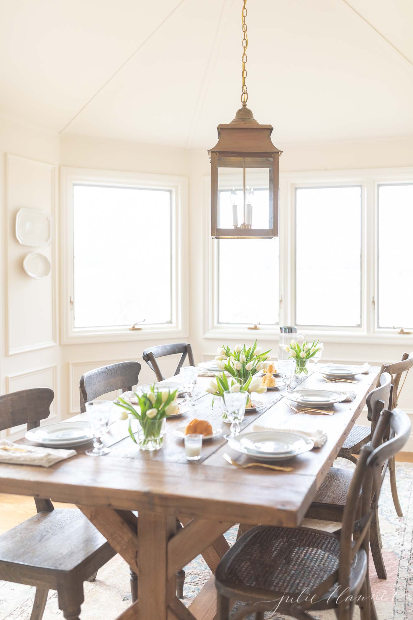 Easter table decor on a long farm table with a brass lantern above