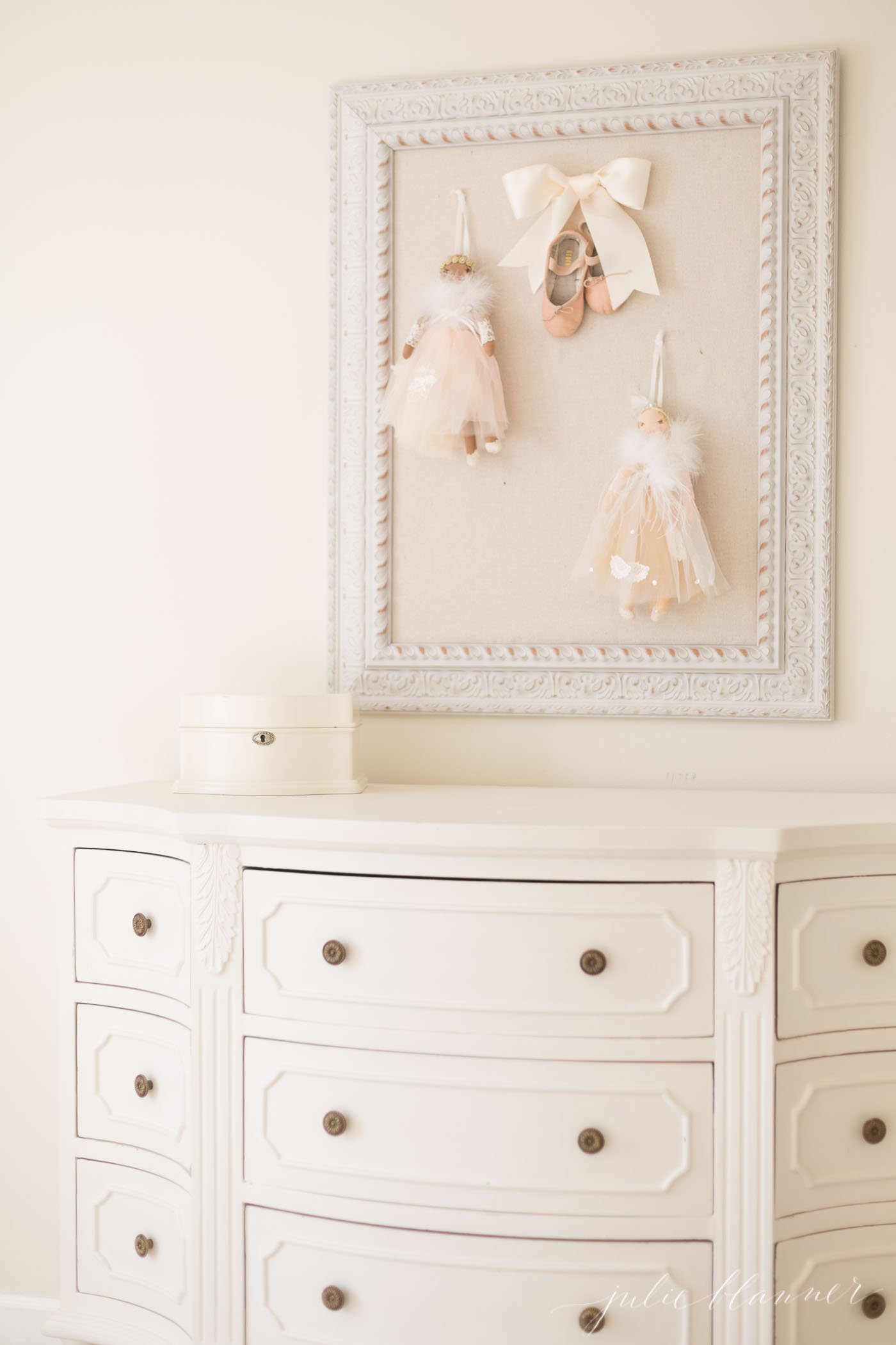 A little girl's bedroom scene with a white painted dresser and white pinboard with ballet details.