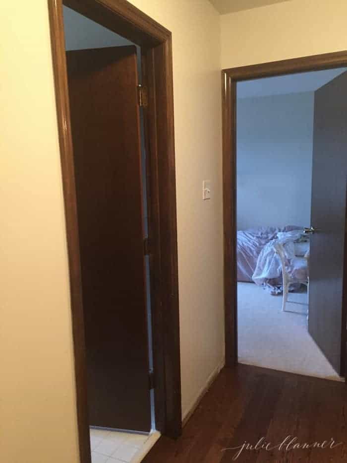 A dark hallway with dark wooden doors and trim.