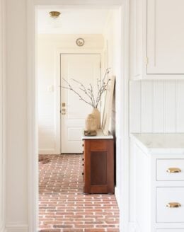 Wood vases on a vintage table in a white mudroom.