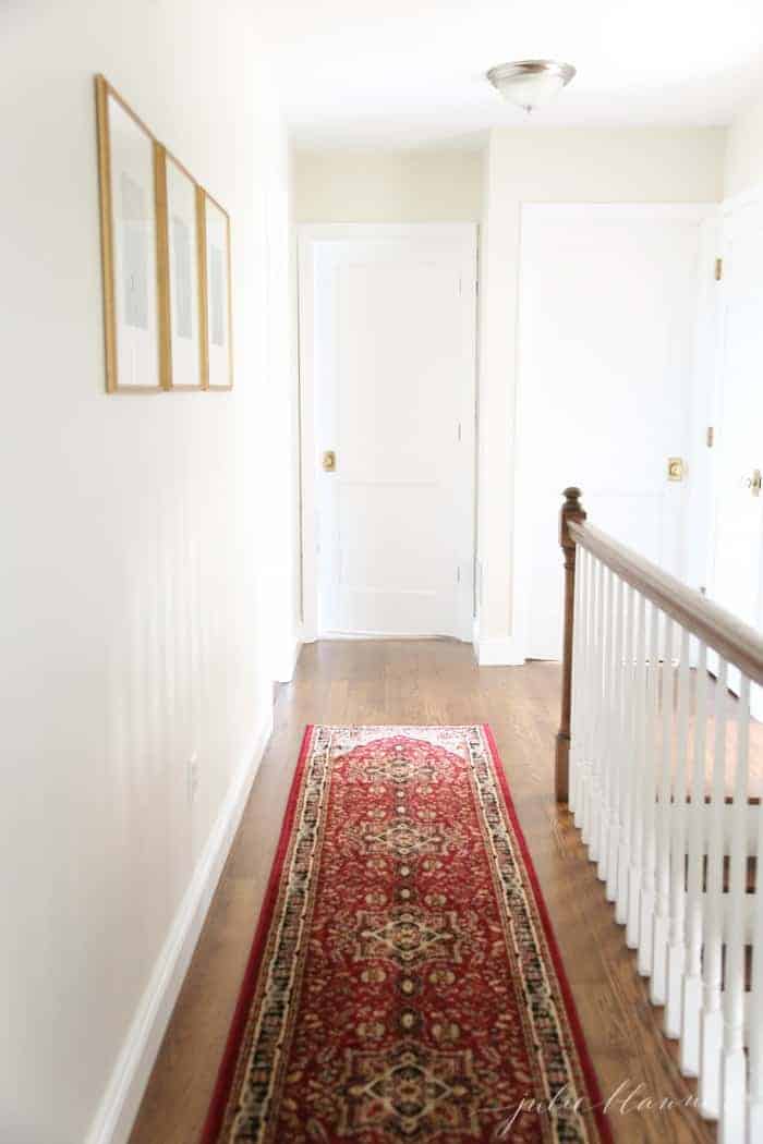 A white painted hallway with a red runner on hardwood floors