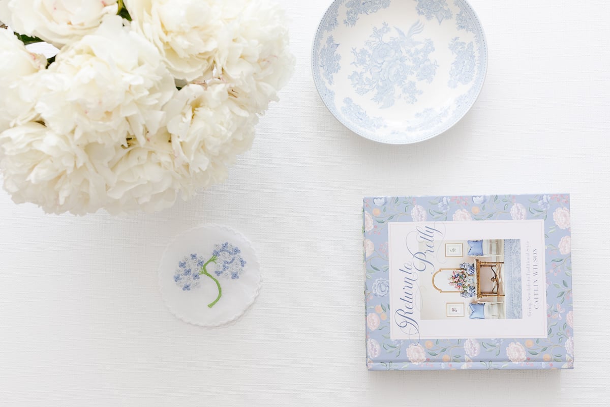 A white living room with an arrangement of white Trader Joe's flowers in a vase on the coffee table.