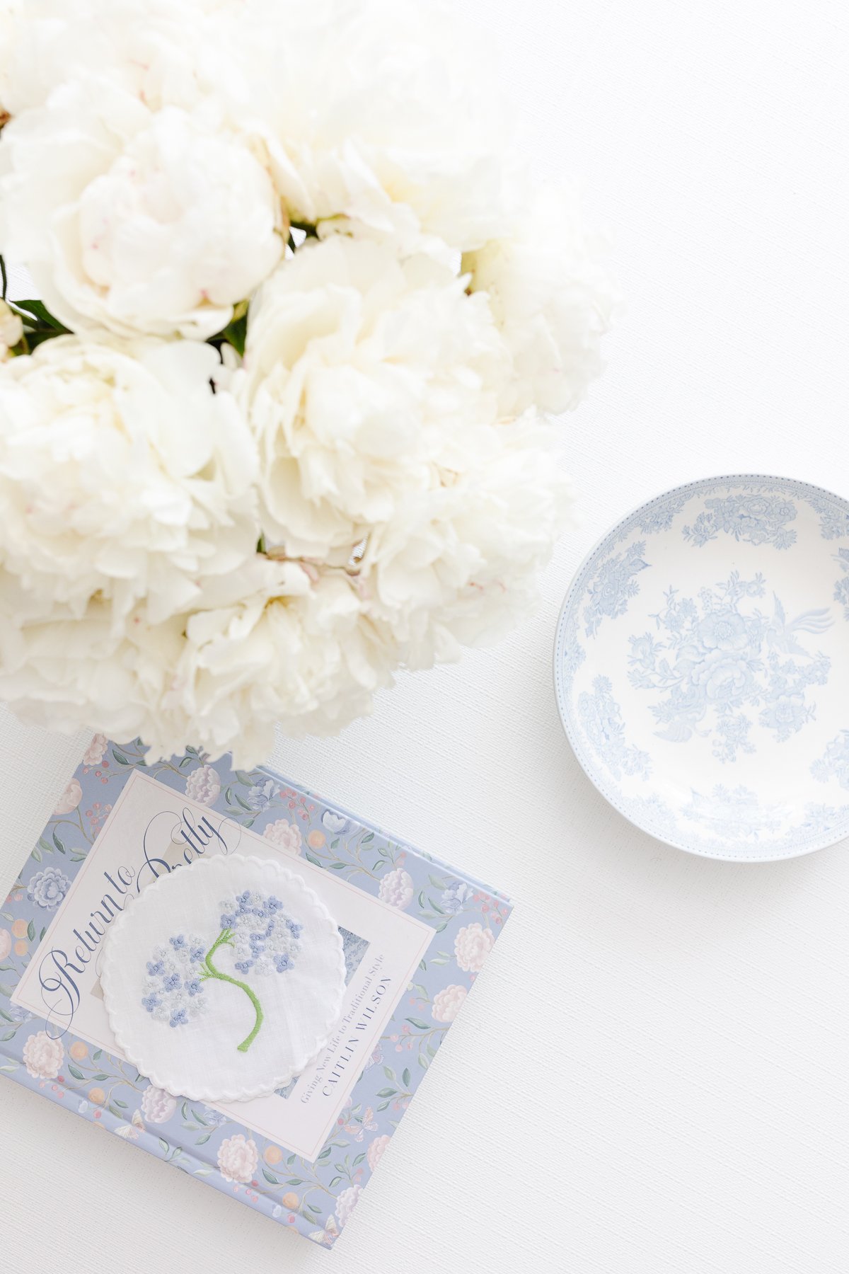 A white living room with an arrangement of white Trader Joe's flowers in a vase on the coffee table.