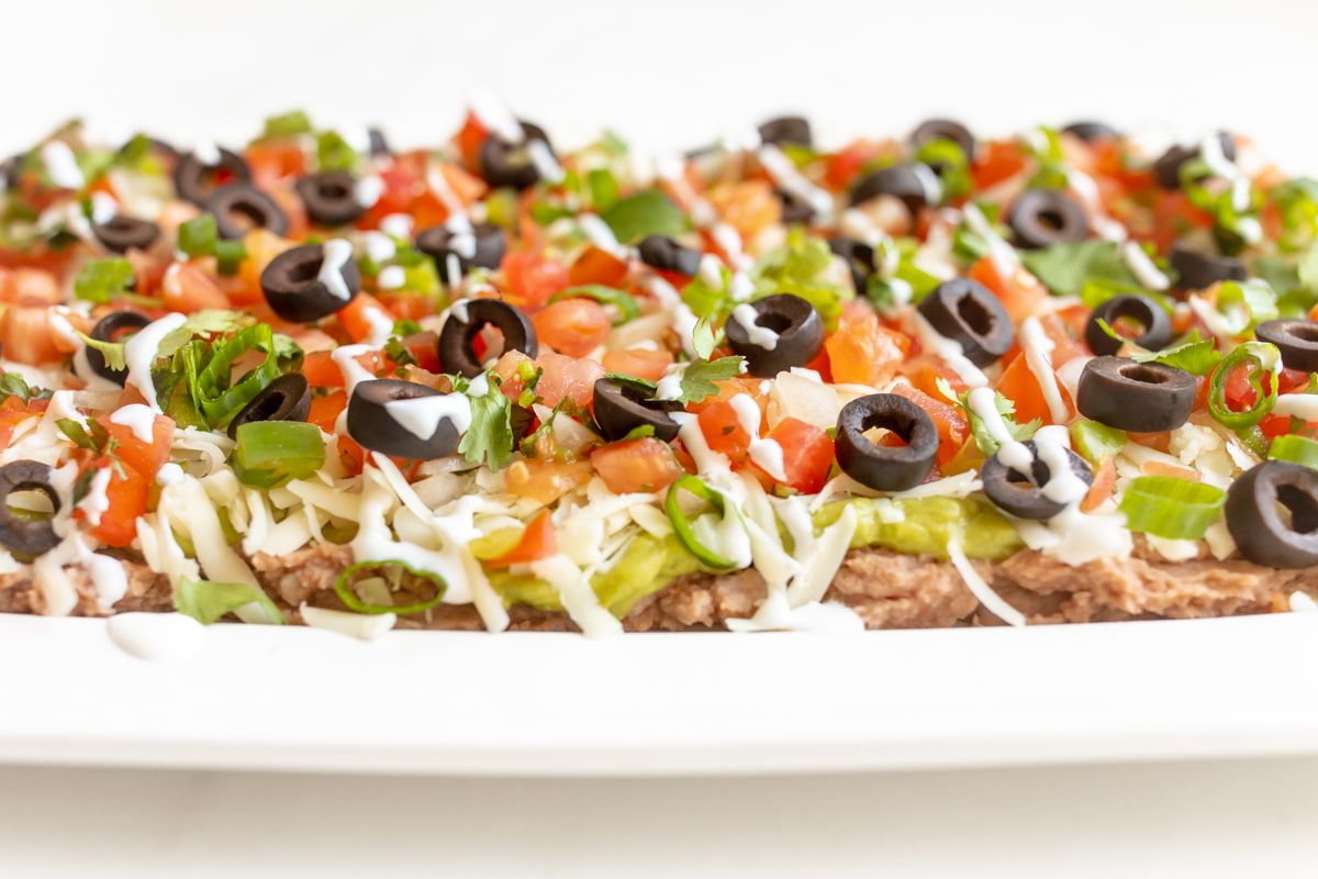 A white platter full of seven layer dip.