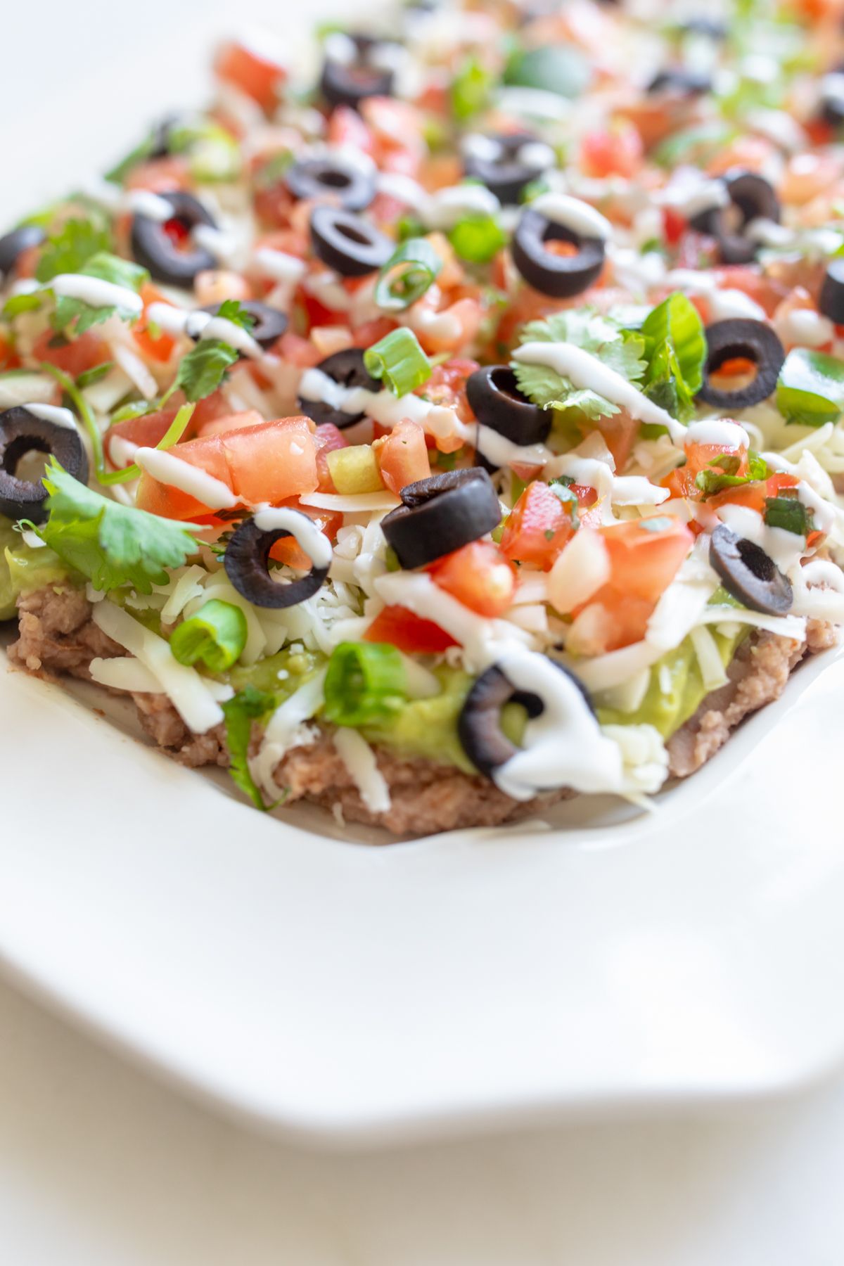 A white platter full of seven layer dip.