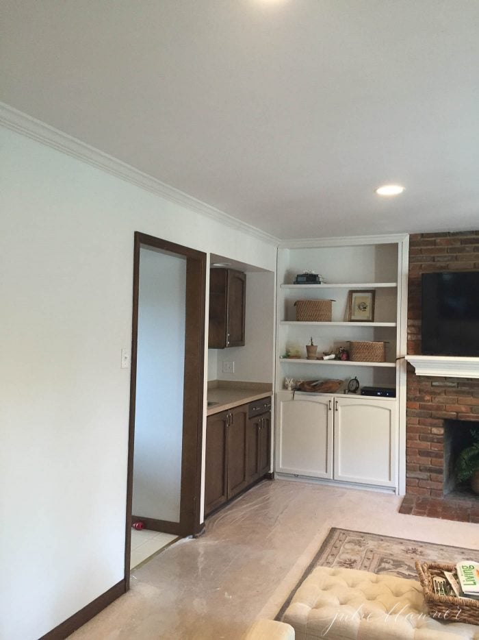 A room with a brick fireplace and various white accents.