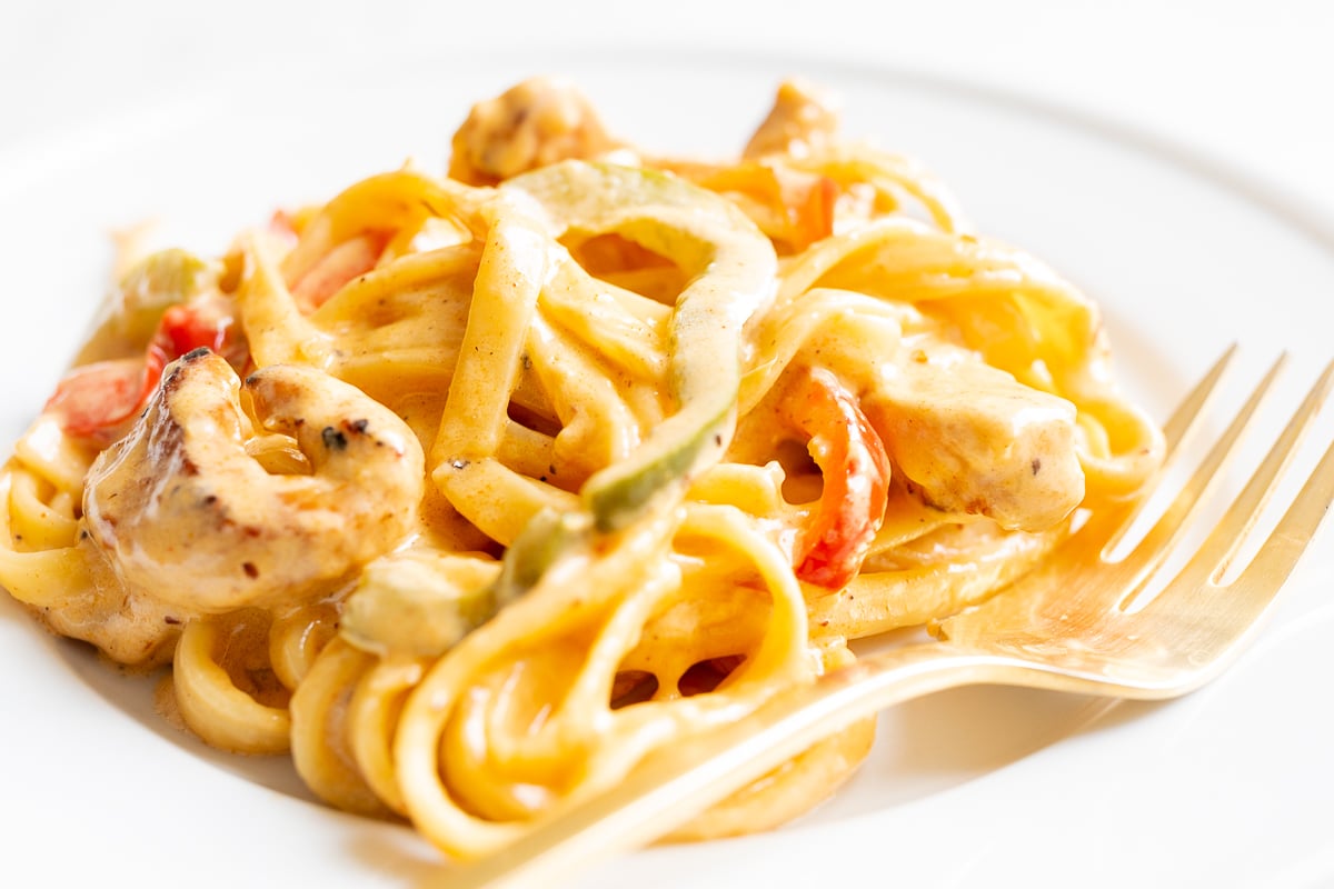 A white plate with a serving of Cajun chicken pasta.