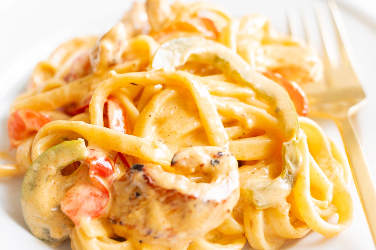 A white plate with a serving of Cajun chicken pasta.