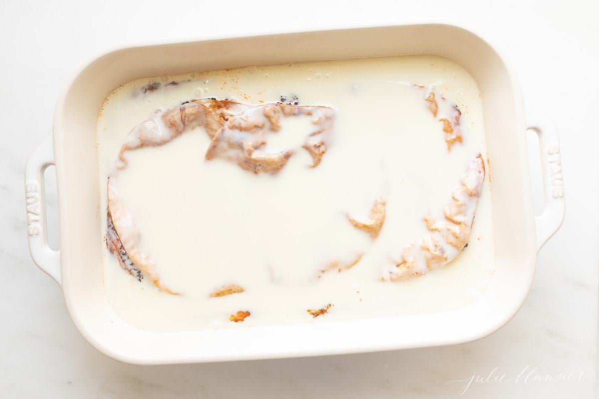 A breakfast burrito casserole being put together in a white baking dish