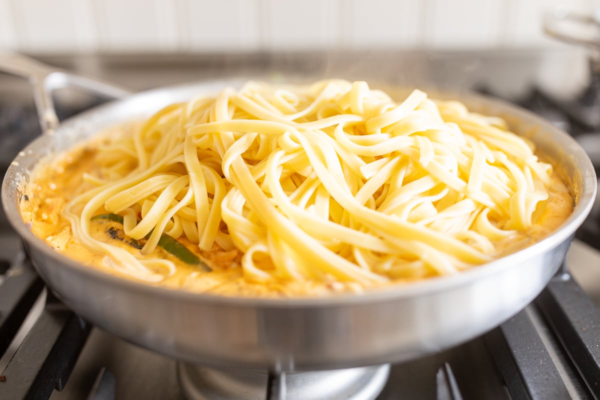 cajun chicken pasta in a stainless steel pot on a gas stovetop