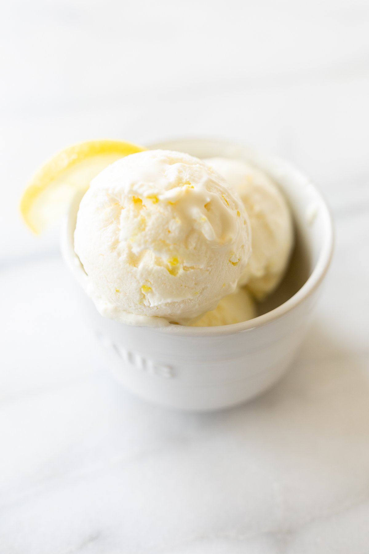 A white bowl full of homemade no churn lemon ice cream with condensed milk.