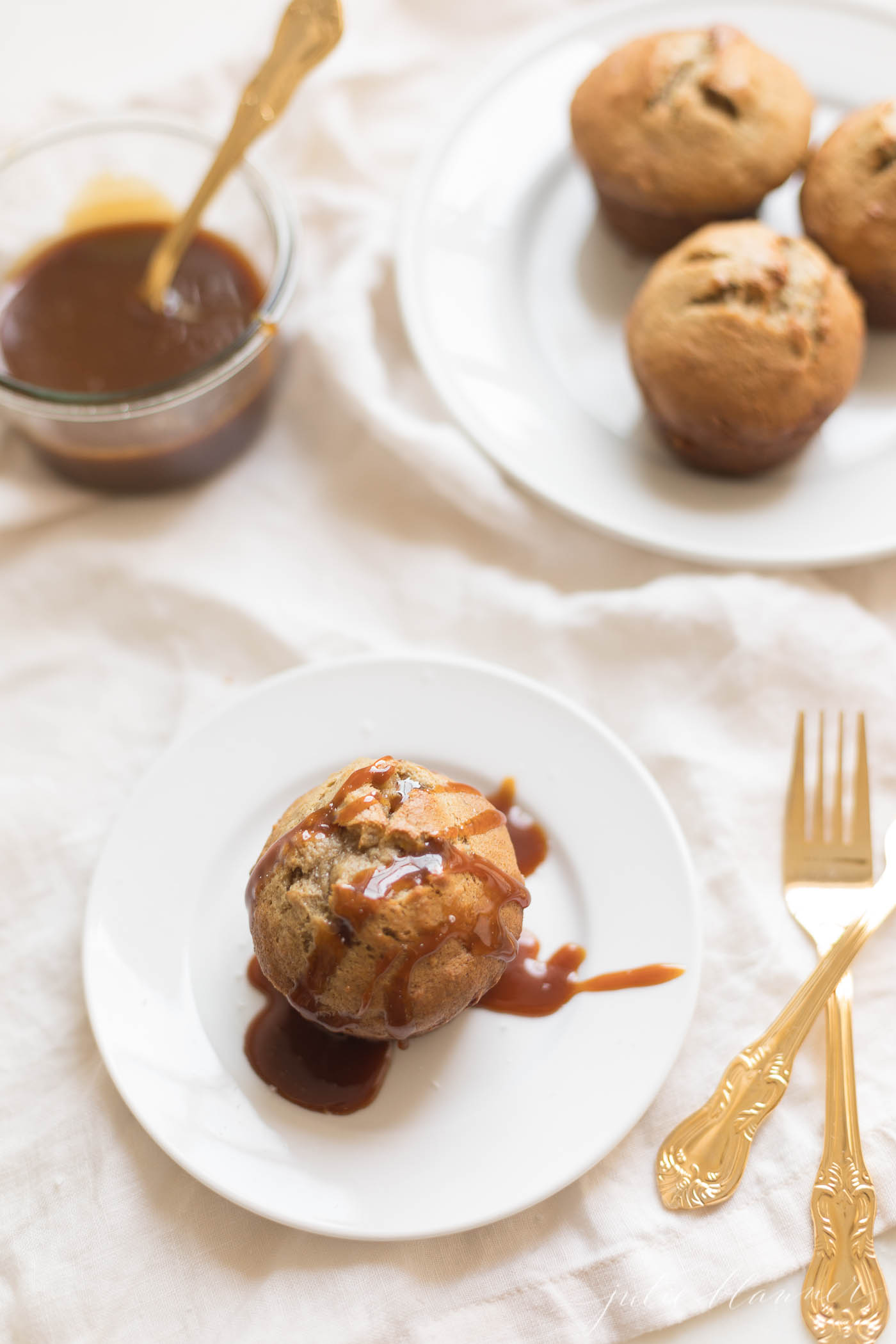 Caramel and Banana Muffin on a white plate, gold silverware to the side.