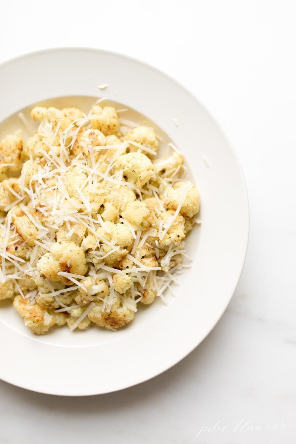 fiesta ranch roasted cauliflower on a white plate, topped with grated parmesan cheese.