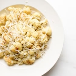 fiesta ranch roasted cauliflower on a white plate, topped with grated parmesan cheese.