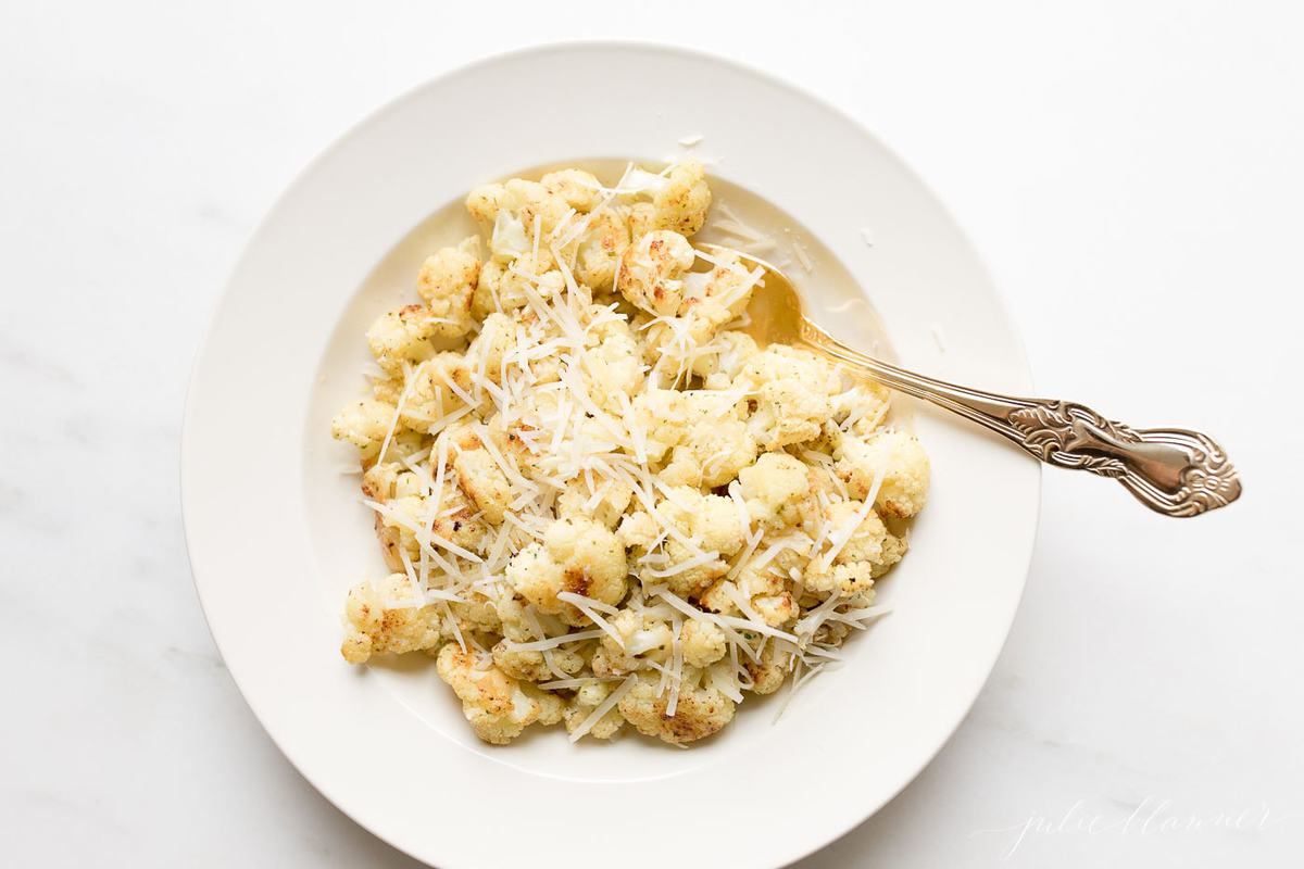 fiesta ranch roasted cauliflower on a white plate, topped with grated parmesan cheese.