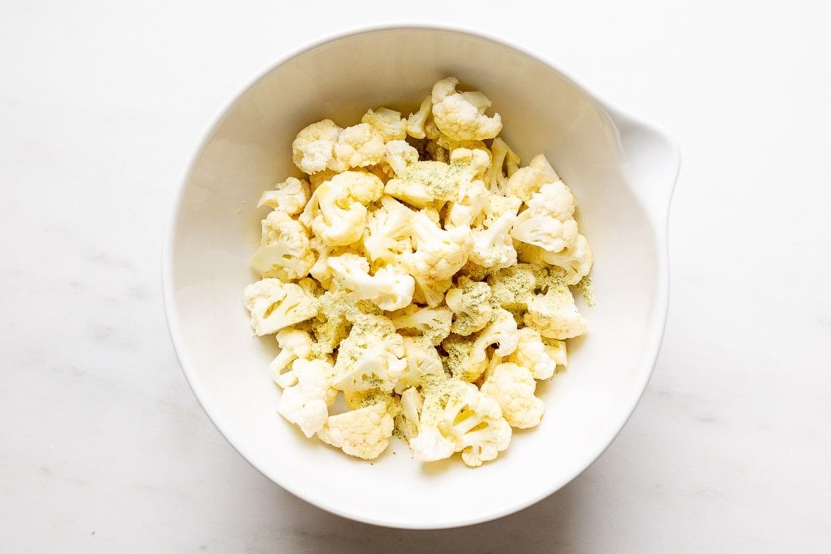 A white bowl of chopped cauliflower florets.