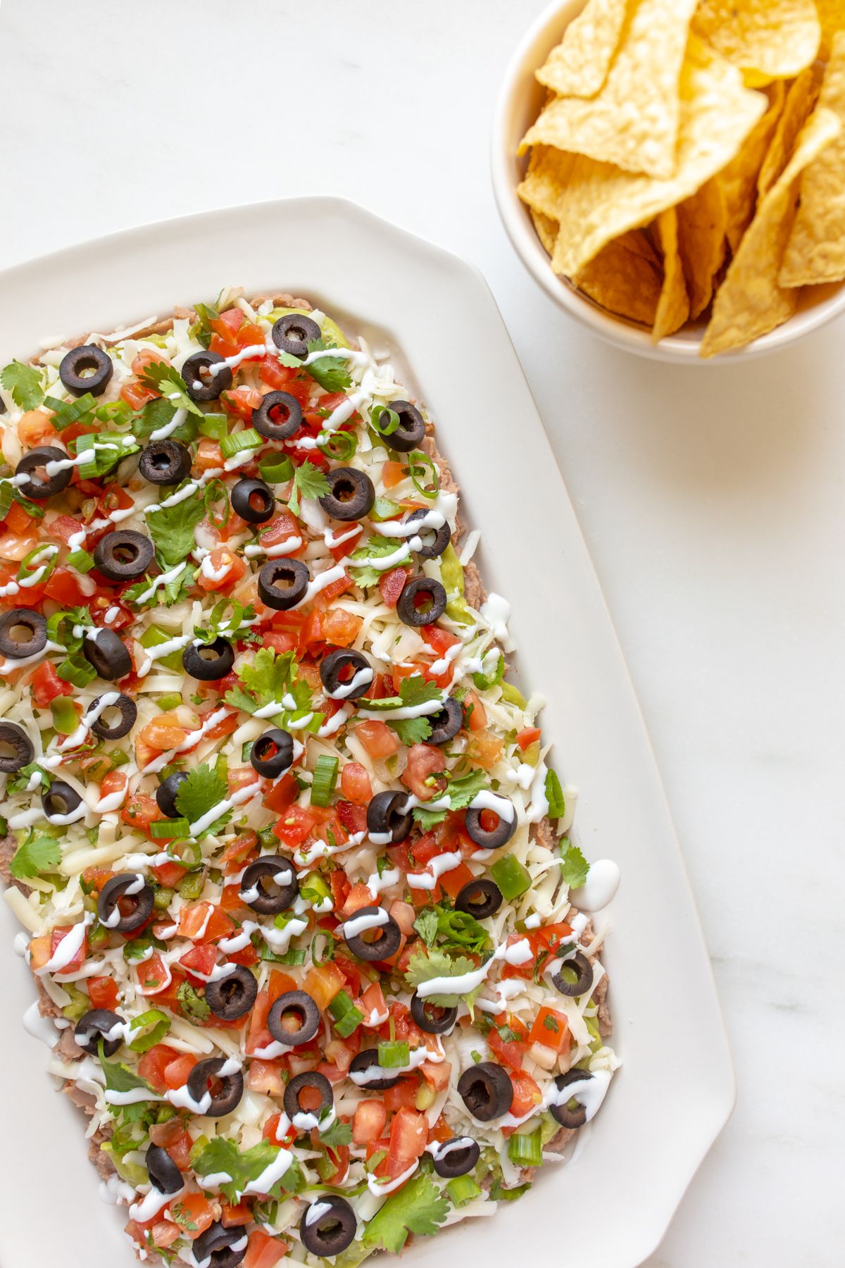 A white platter full of seven layer dip.