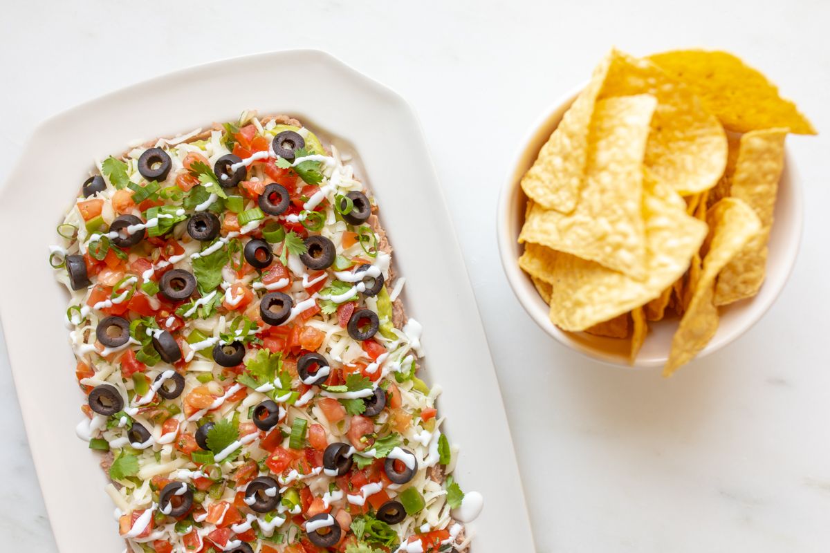 A white platter full of seven layer dip.