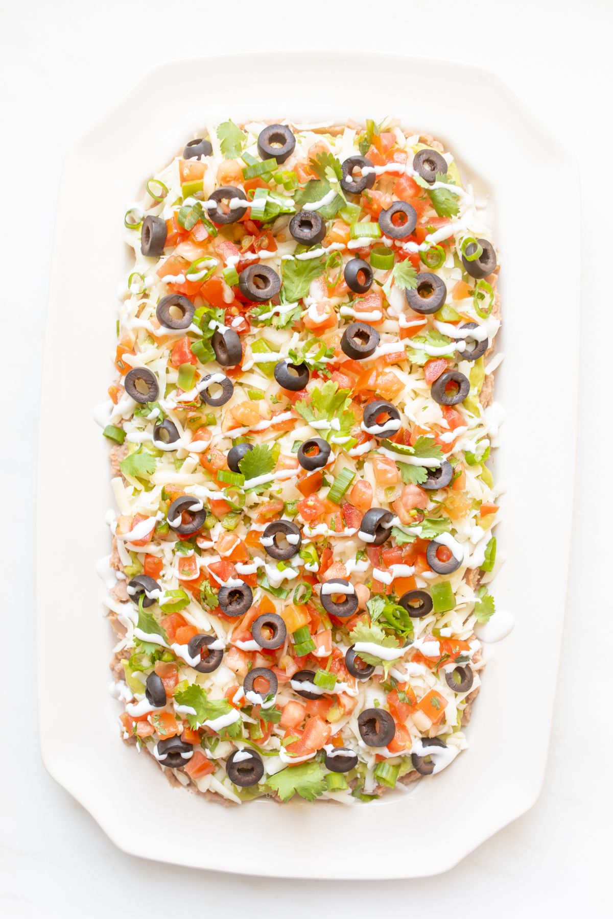 A white platter full of seven layer dip.