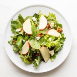 A white plate filled with an apple salad.