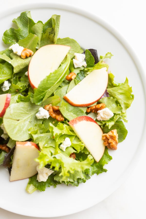 A white plate filled with an apple salad.