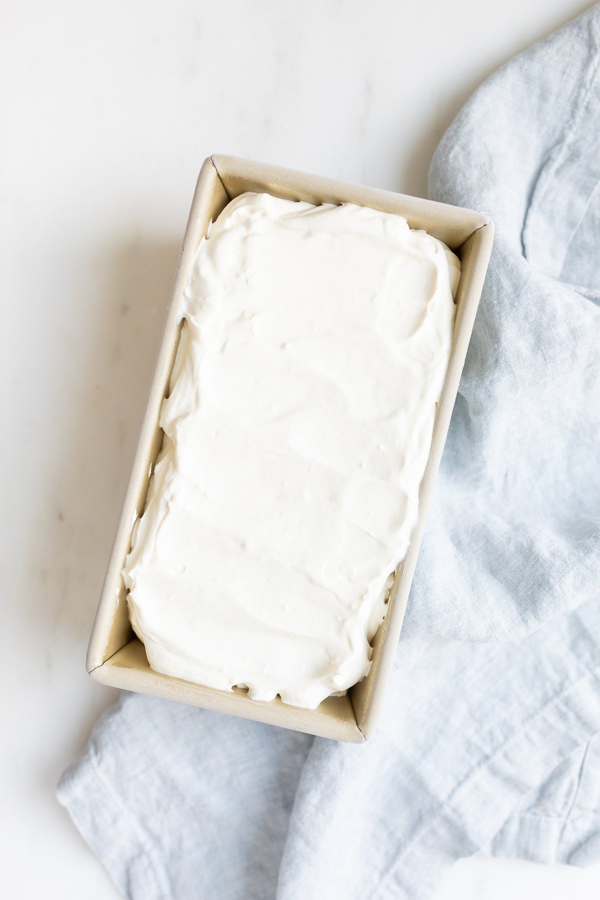 cream cheese ice cream in a container on blue napkin