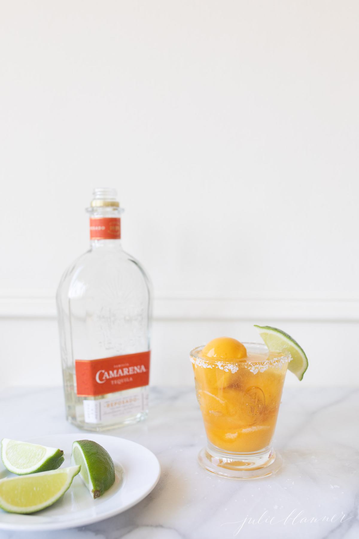 mango margarita float next to a bottle of tequila