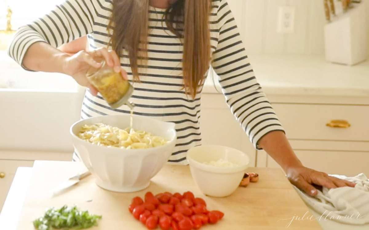 pouring pasta salad dressing onto pasta salad