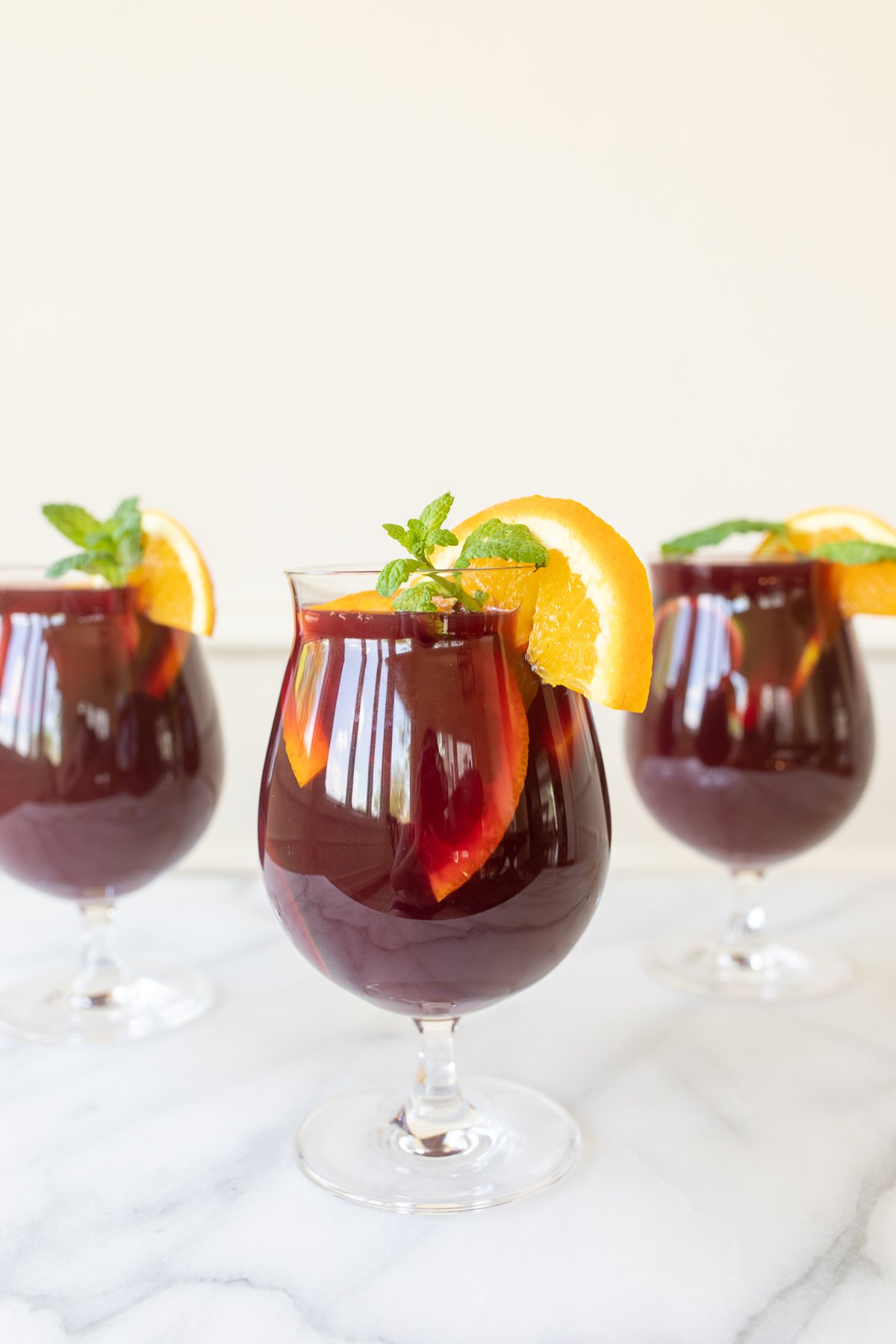 Traditional red sangria in stemware, garnished with fresh mint and orange slices.