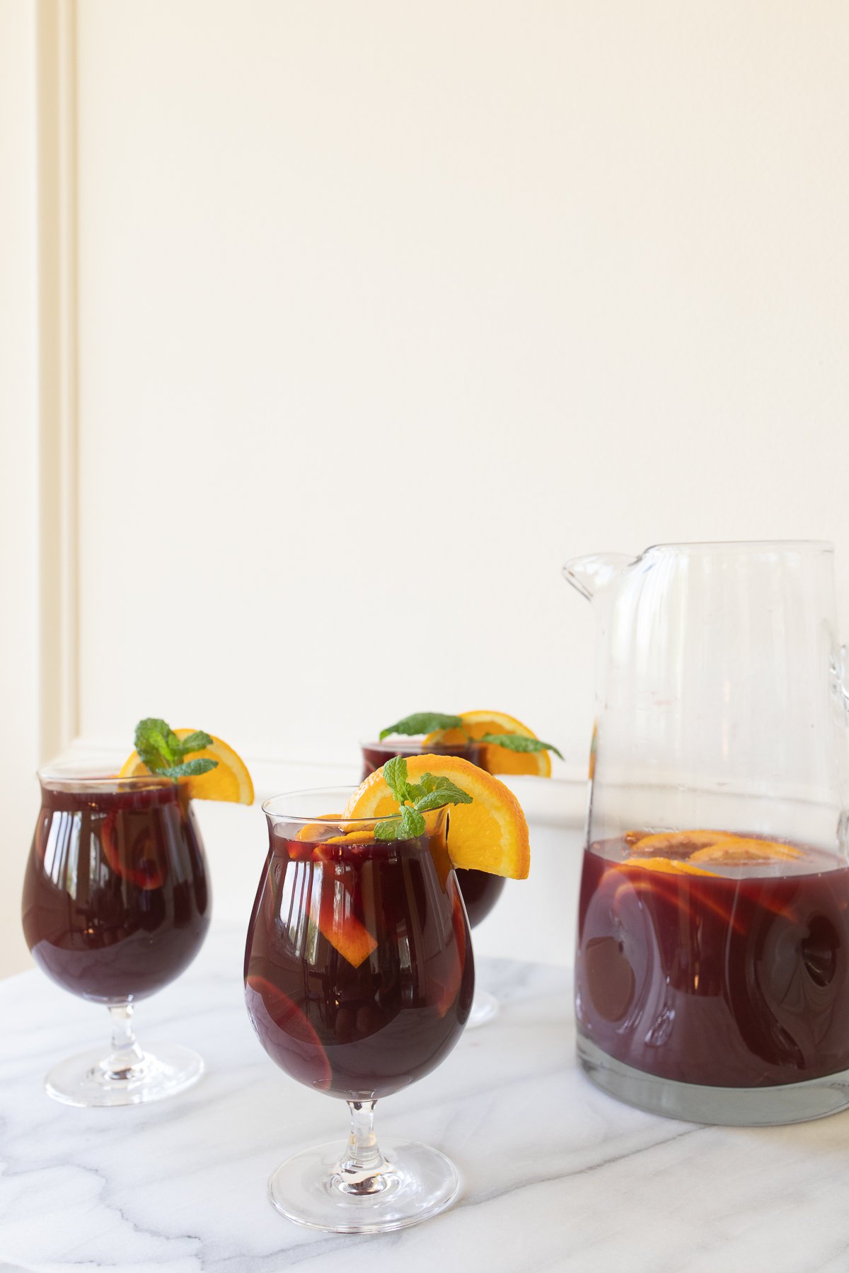 Traditional red sangria in stemware, garnished with fresh mint and orange slices.